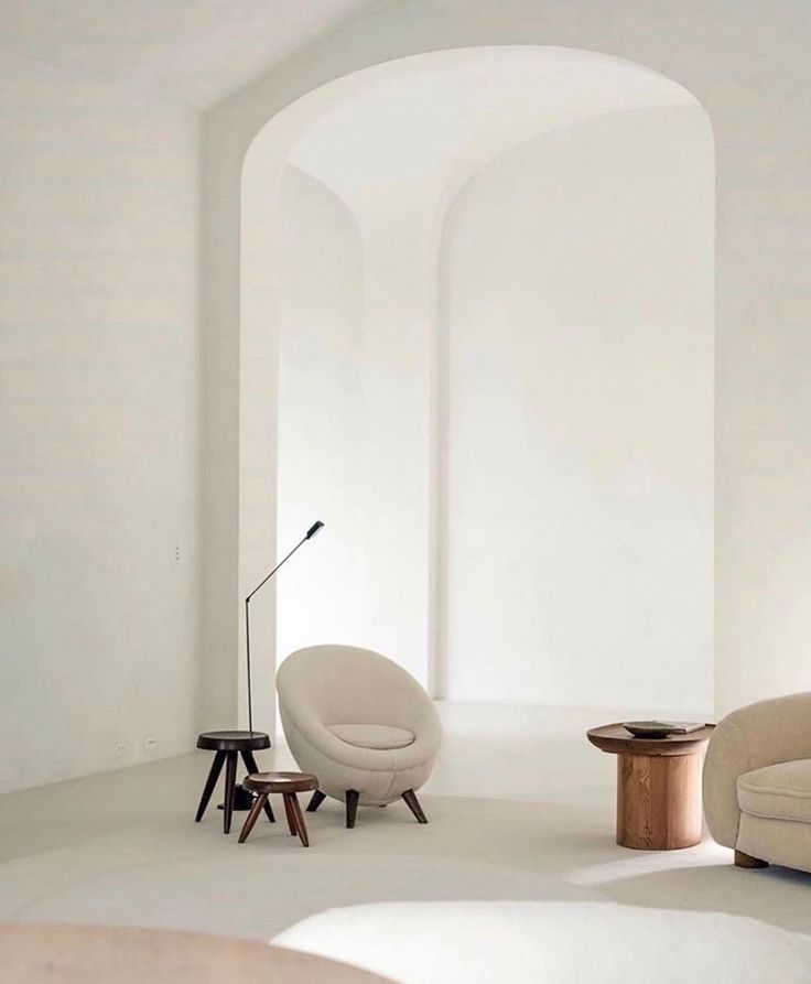 a living room with two chairs and a table in the middle, all white walls