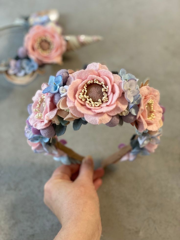 a hand holding a flower headband made out of fabric flowers