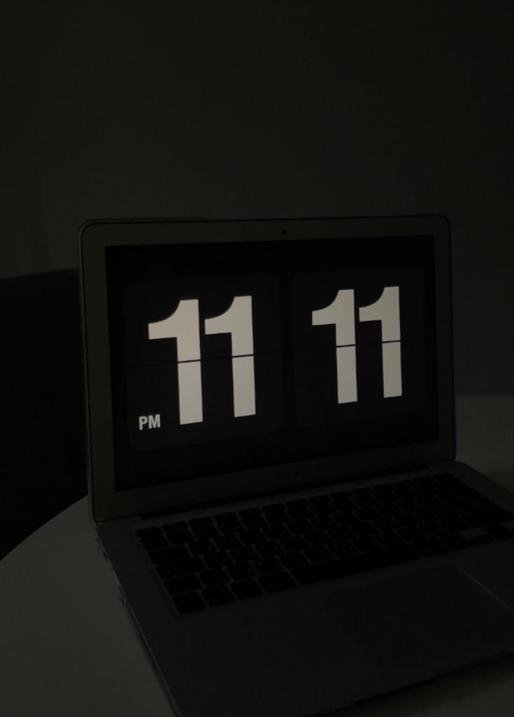 an open laptop computer sitting on top of a white table next to a black clock