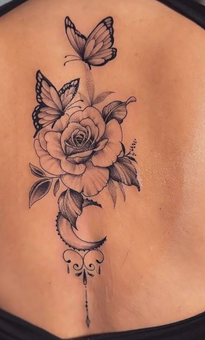 a woman's back with a butterfly and rose tattoo on her left side ribcage