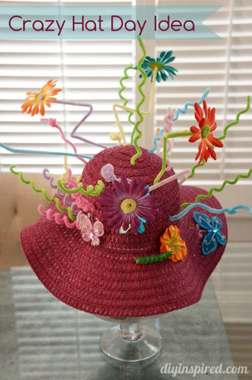 a red hat with flowers and streamers is sitting on top of a glass table