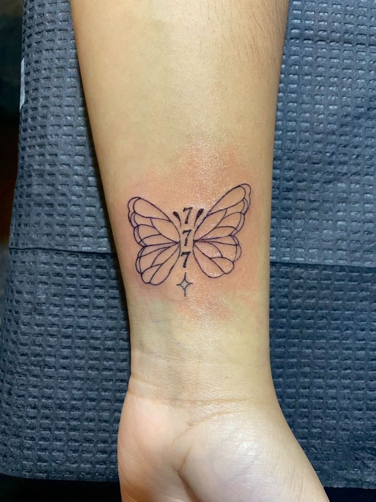 a small butterfly tattoo on the left wrist is shown in black ink, and it appears to be an outline