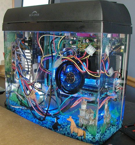 a computer case sitting on top of a desk covered in assorted wires and gadgets