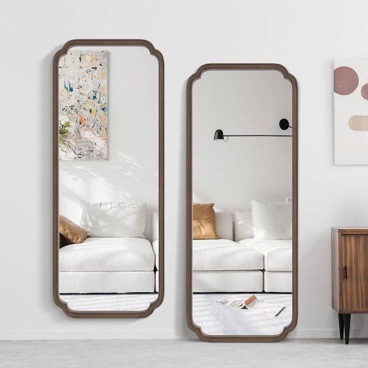 two mirrors sitting next to each other on top of a white wall in a living room