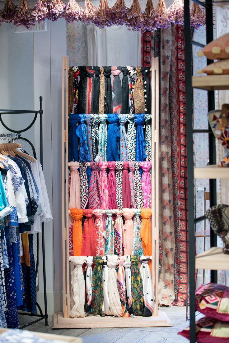 an assortment of scarves are displayed in a clothing store with hanging racks and shelves