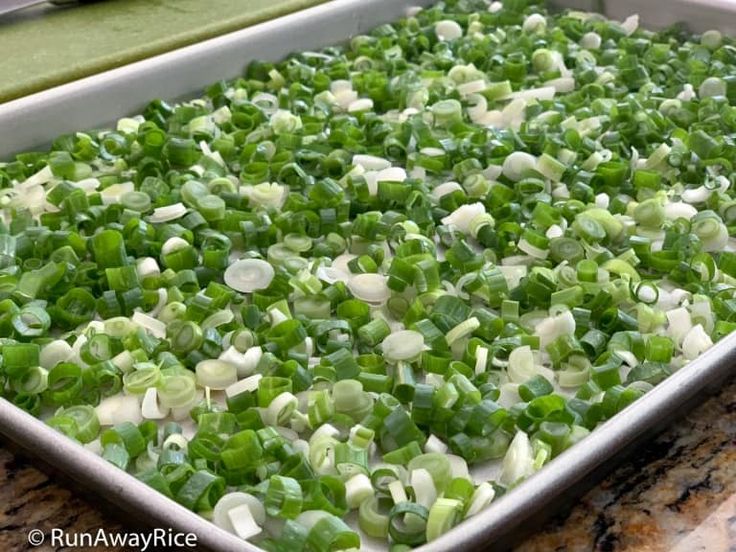 a pan filled with green onions on top of a counter