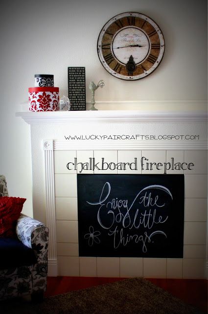 a fireplace with a chalk board on the mantle next to it and a clock above it