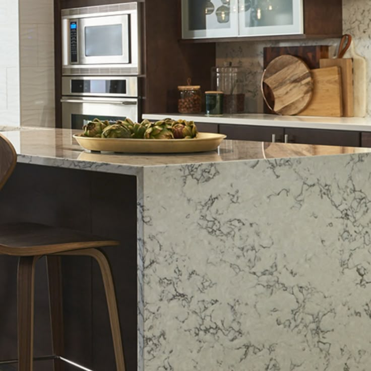 a kitchen with marble counter tops and bar stools in front of the stove top