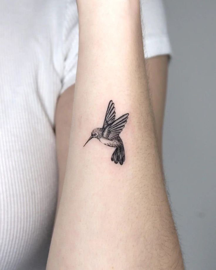 a small hummingbird tattoo on the left inner arm and wrist, it is black and white