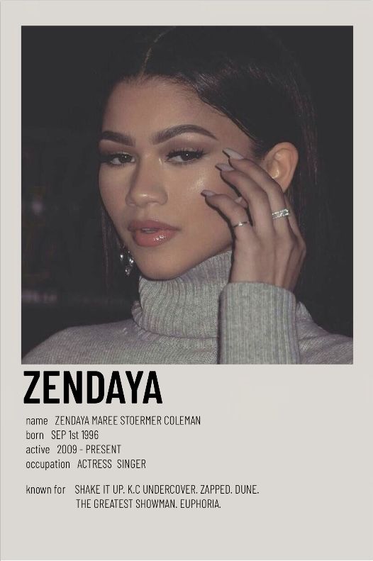 a woman in grey sweater holding her hand up to her face with the words zendaya on it