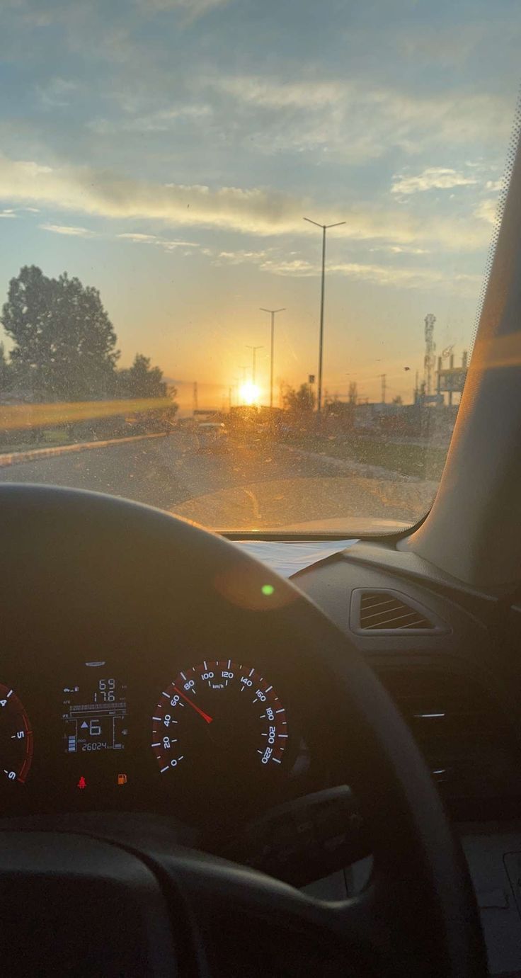 the sun is setting in the distance as seen from inside a vehicle's dashboard