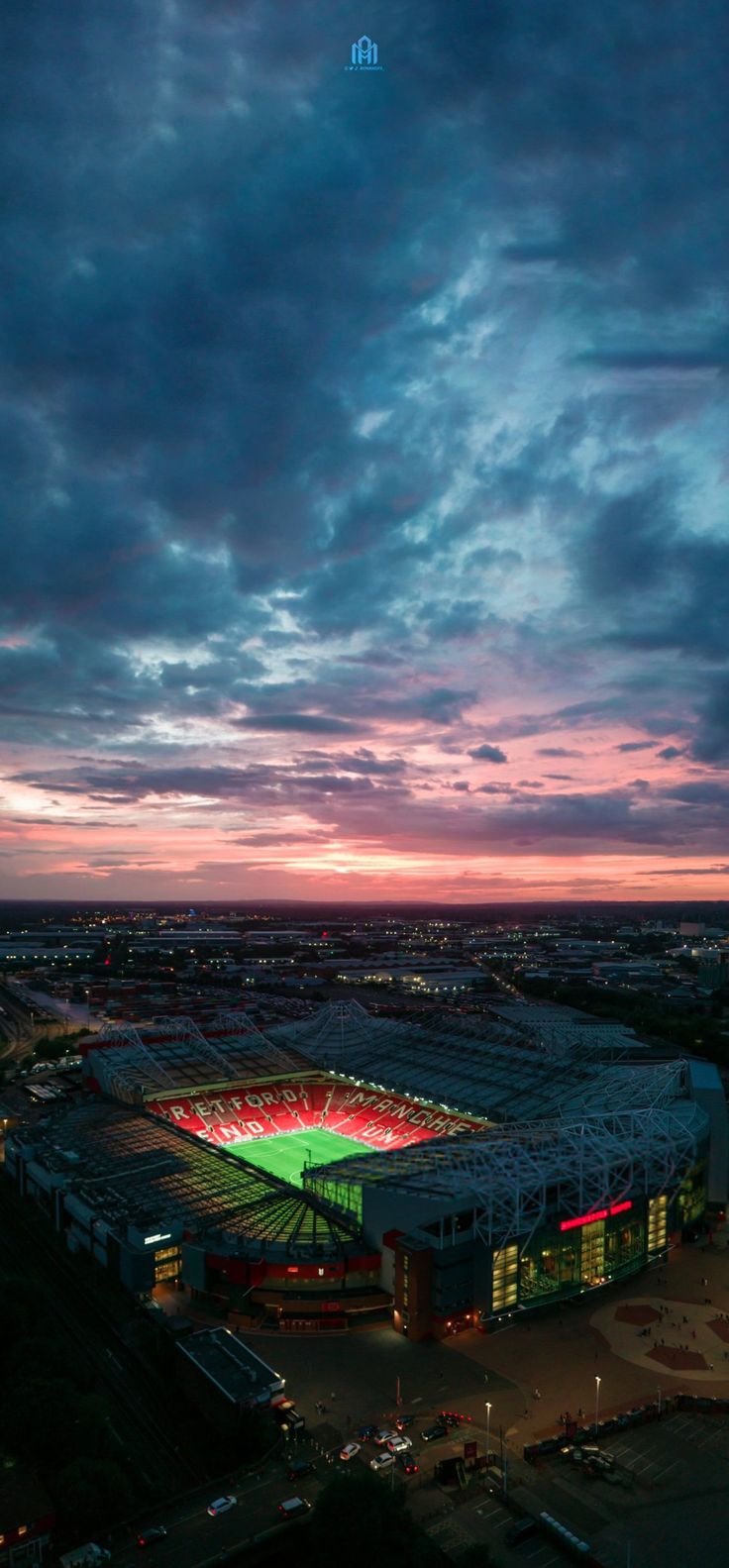 an aerial view of a soccer stadium at night with the sun setting in the background