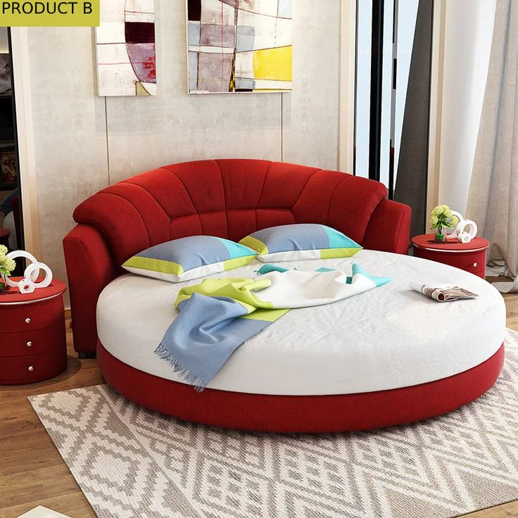 a red round bed sitting on top of a wooden floor next to a white rug