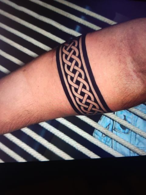 a man's arm with a tattoo on it, in front of a black and white striped background