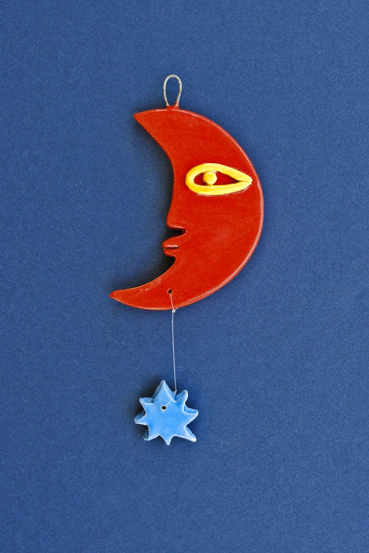 an ornament shaped like the moon and star hanging on a blue background,