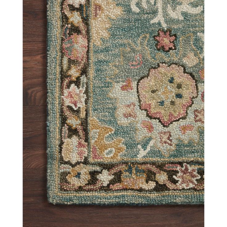 a blue rug with an ornate design on the top and bottom, sitting on a wooden floor