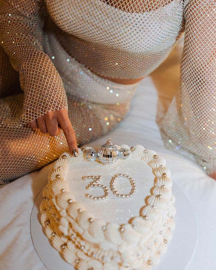 a woman is cutting into a cake with the number 30 on it