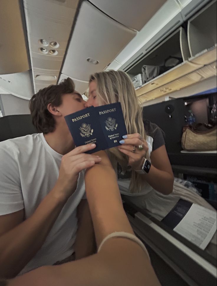 a man kissing a woman on the cheek while she holds up a passport in front of her face