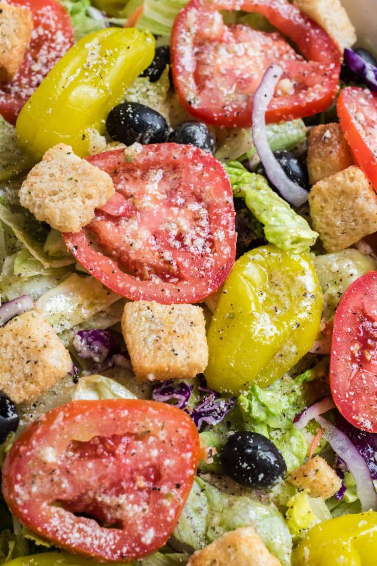 a salad with croutons, tomatoes, lettuce and black olives