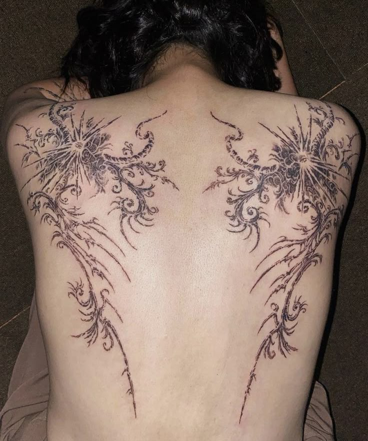 the back of a woman's body with tattoos on it