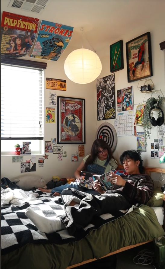 two people sitting on a bed in a room with posters hanging above the headboard