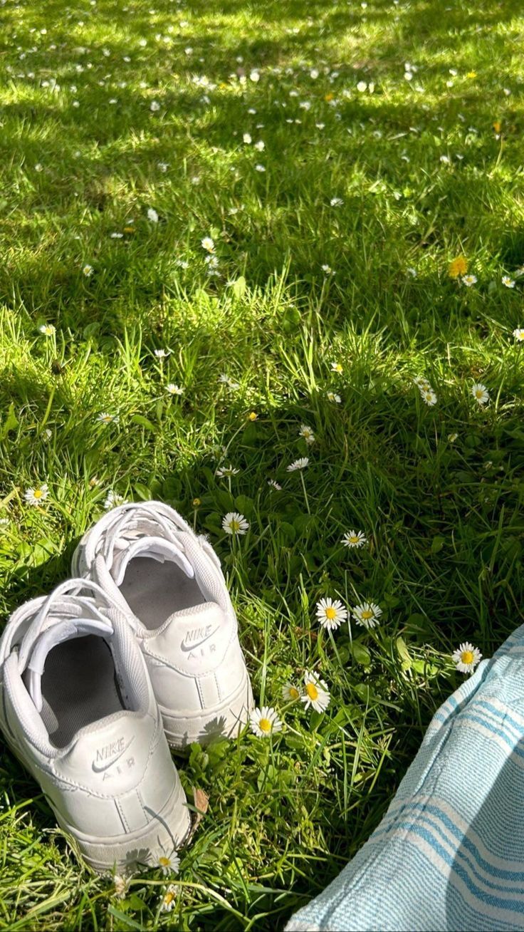 a pair of white shoes sitting on top of a lush green field