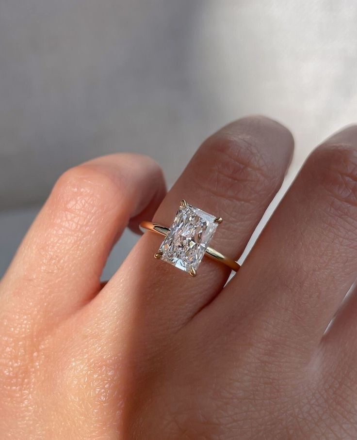 a woman's hand with a diamond ring on top of her finger and the other hand holding an engagement ring