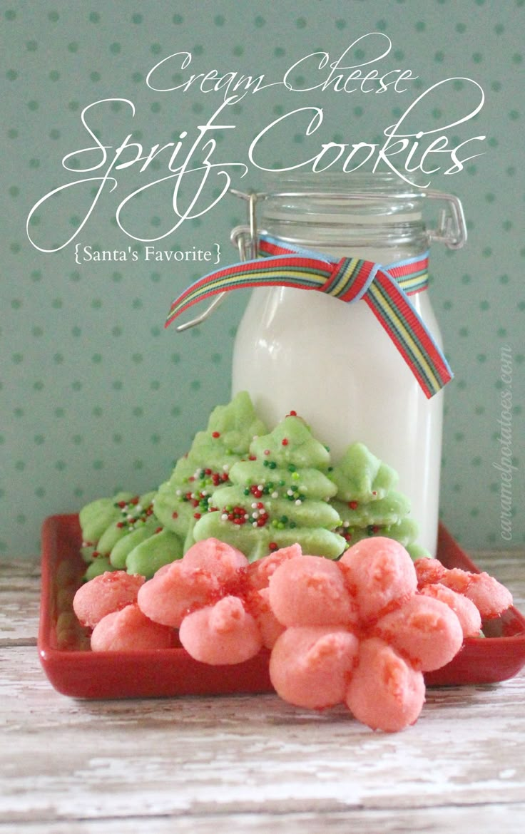 some cookies are sitting on a plate next to a glass jar with white frosting and sprinkles