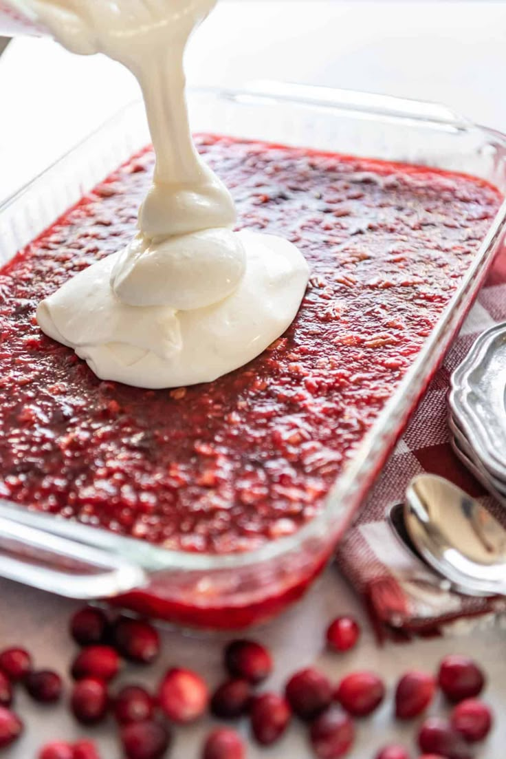 cranberry sauce being drizzled with icing in a glass dish