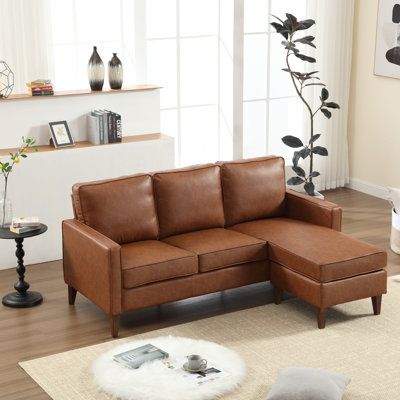 a brown leather sectional sofa in a living room with white rugs and large windows