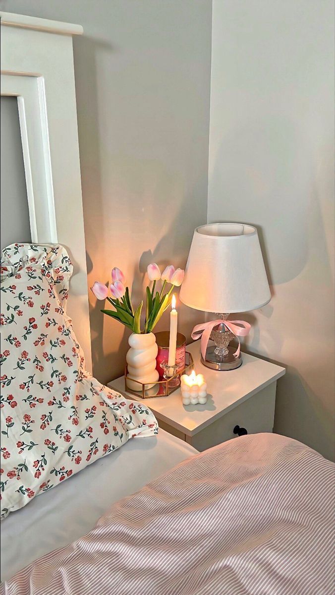 a white bed topped with two nightstands next to a night stand filled with flowers