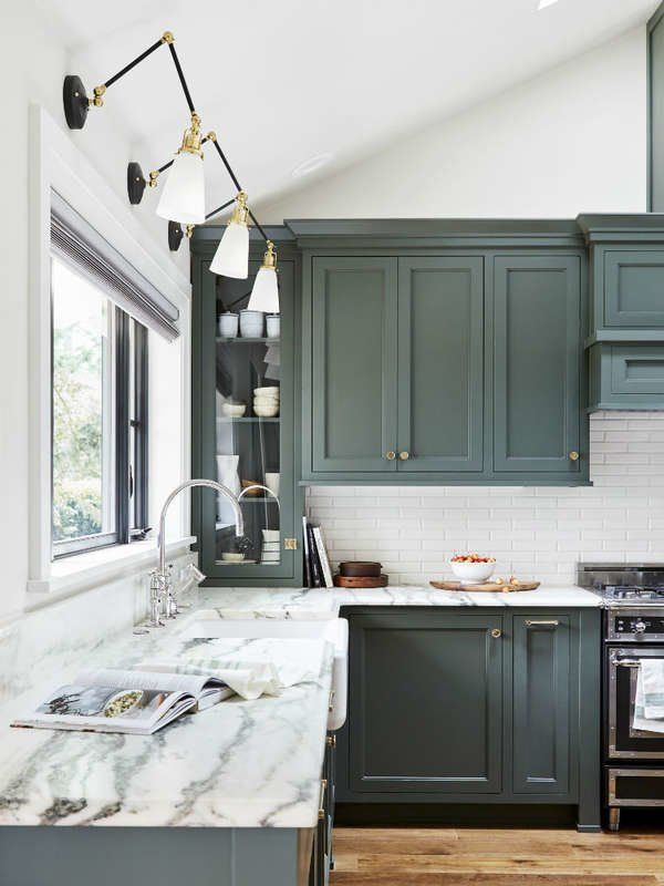 a kitchen with green cabinets and marble counter tops