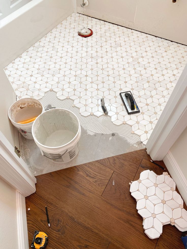 a bathroom floor that is being remodeled with tools on the ground and in buckets next to it