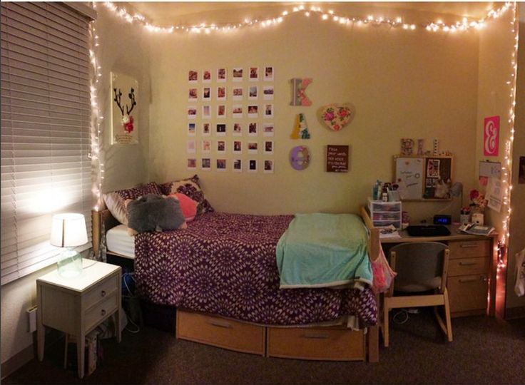 a dorm room with lights strung over the bed and desks in front of it