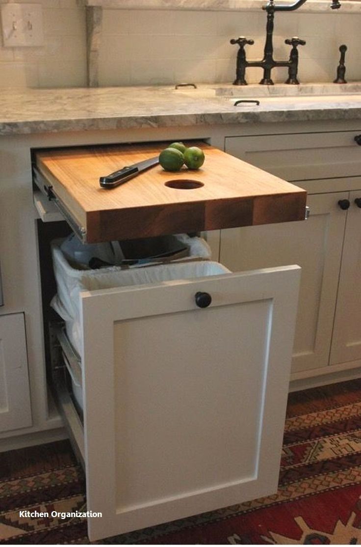 a kitchen with white cabinets and wooden cutting board in the middle of the cabinet drawer