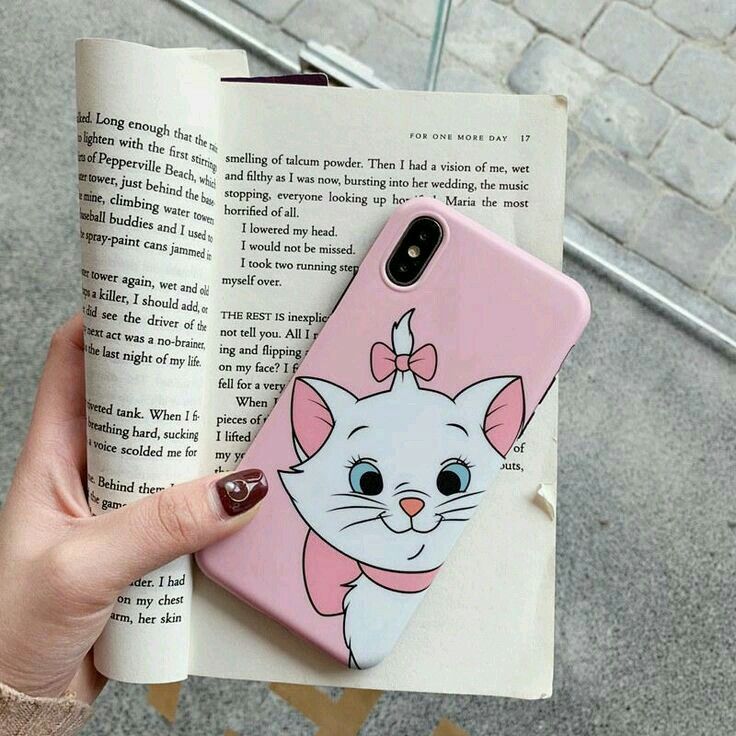 a person holding an open book with a cat phone case on it's cover