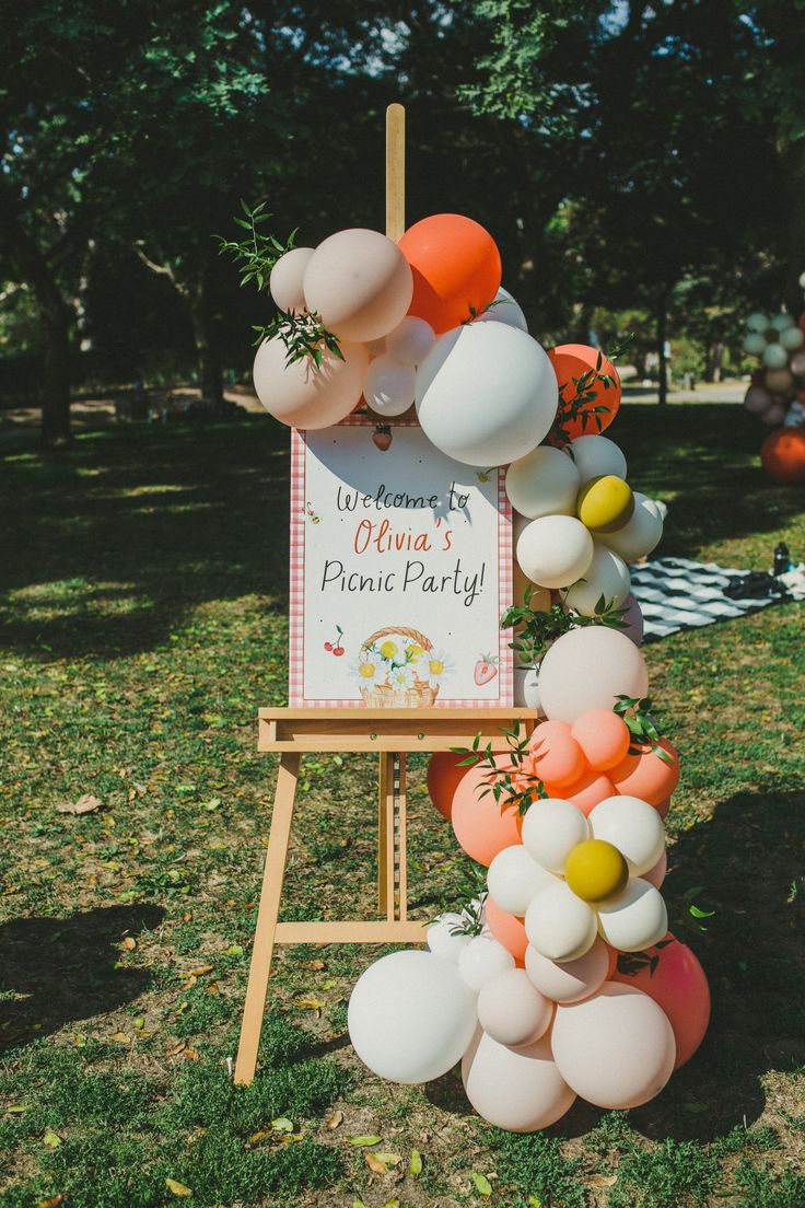 a sign with balloons attached to it in the grass