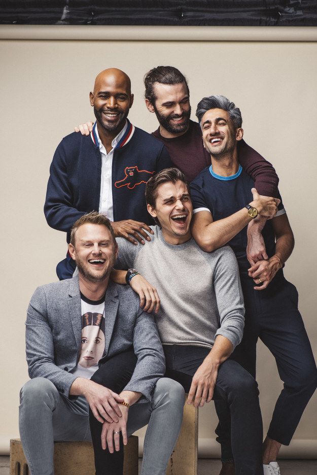 four men are posing for the camera with one man holding his arm around another man's shoulder