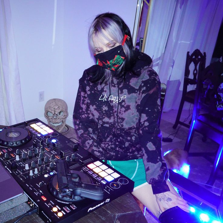 a woman wearing a bandana standing in front of a dj's equipment