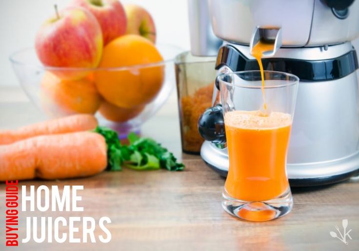 an orange juice being poured into a glass next to carrots and other fruits on a table