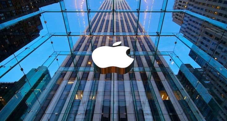 an apple logo is reflected in the glass walls of a building