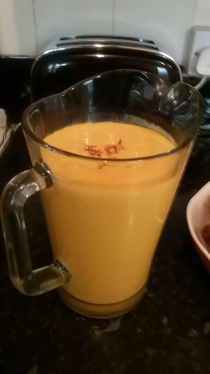 a glass pitcher filled with liquid sitting on top of a counter next to a bowl