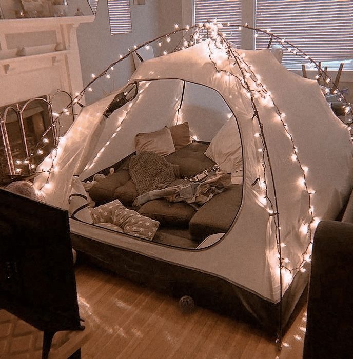 a tent that has been set up in the middle of a room with lights on it