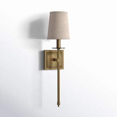 a wall light with a white shade on it's side and a lamp attached to the wall