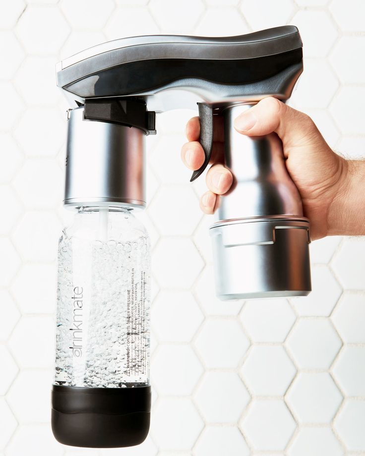 a person is holding a water bottle and a faucet in front of a white tiled wall