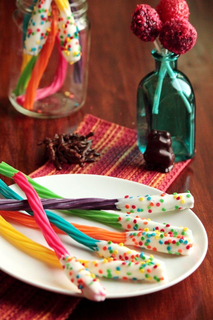 there are many colorful candy sticks on the plate next to some bottles with candies in them