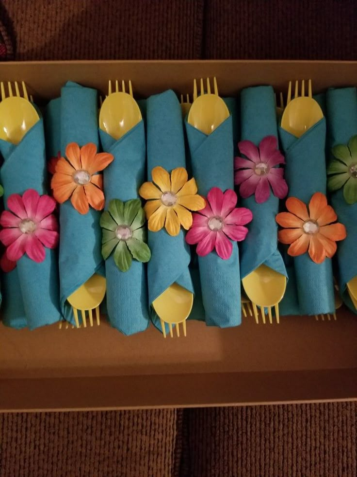 there are many forks and flowers on the blue napkins that have been folded into them