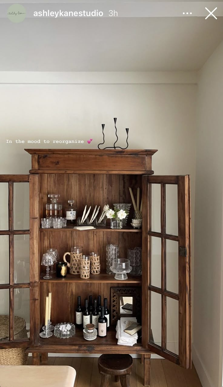 a wooden cabinet filled with lots of bottles and glasses on top of a hard wood floor