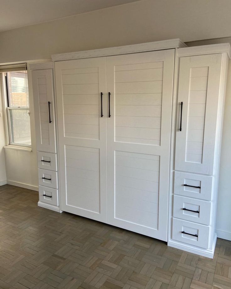 an empty room with white cabinets and wood floors