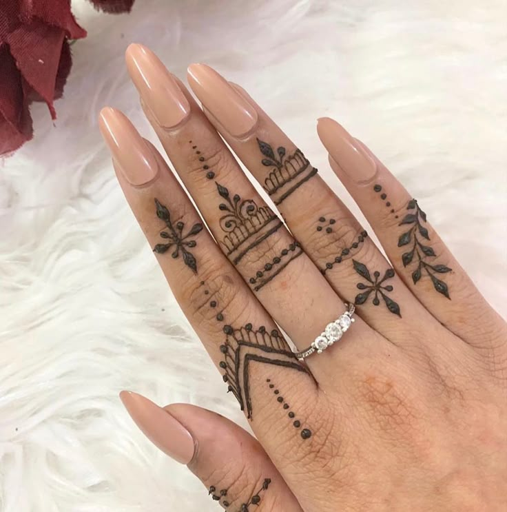 a woman's hand with henna tattoos on it and her wedding ring in the middle